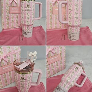 May include: A pink and white floral patterned Stanley Quencher H2.0 tumbler with a handle, straw, and lid. The tumbler is packaged with a matching gift box and a pink cloth. The tumbler has the Stanley logo and the words "Loves Fancy" printed on it.
