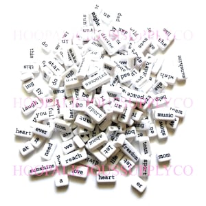 May include: A pile of small, white rectangular beads with black printed words. The words include "love", "heart", "sunshine", and "freedom". These beads are ideal for jewelry making and crafting.