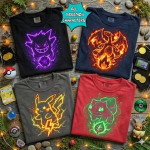 Puede incluir: Cuatro camisetas gráficas con personajes de Pokémon. Las camisetas son negras, azul marino, grises y rojas. La camiseta negra tiene un diseño de Gengar morado, la camiseta azul marino tiene un Charizard ardiente, la camiseta gris tiene un diseño de Pikachu y la camiseta roja tiene un diseño de Bulbasaur. El texto "ALL POKEMON CHARACTERS" está en una burbuja turquesa.