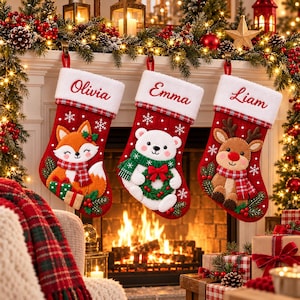May include: Three red Christmas stockings with white cuffs featuring the names Olivia, Emma, and Liam. The stockings display felt appliques of a fox, a polar bear, and a reindeer, each wearing a plaid scarf, accented with snowflakes.