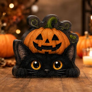 May include: A decorative wooden cutout featuring a black cat with large yellow eyes and paws resting below a carved orange jack-o'-lantern pumpkin. The design includes a green stem and vine details against a dark, textured background.