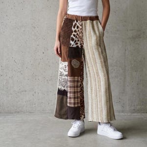 Könnte beinhalten: Weite Patchwork-Hose mit verschiedenen braunen und beigen Stoffen, darunter Animal-Print und Karomuster. Die Hose hat eine hohe Taille und wird mit weißen Turnschuhen getragen. Das Design zeigt eine Mischung aus Texturen und Mustern für einen einzigartigen Look.