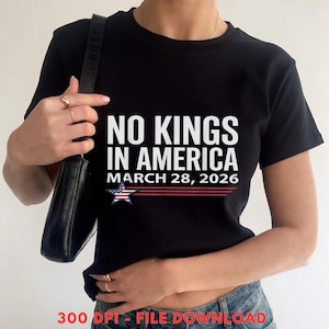 Op de afbeelding: Zwart T-shirt met de witte tekst "NO KINGS IN AMERICA", de datum "MARCH 28, 2026" en een ster. Het shirt heeft een ronde hals.