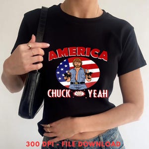 May include: Black t-shirt featuring a graphic of a man holding two guns, set against a backdrop of the American flag. The text "AMERICA" and "CHUCK YEAH" are displayed in red and white.