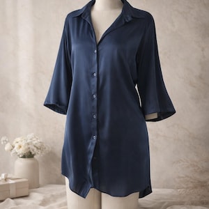 May include: A white ceramic mug with a black handle and the text "But First, Coffee" in a bold, black font. The mug is set against a blurred background, suggesting a cozy setting.