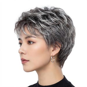 May include: A woman with short, wavy, gray and white hair, wearing silver hoop earrings and a black top. The hairstyle is a short, layered cut with a side part. The earrings are simple, circular hoops.