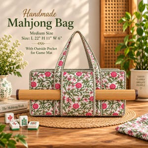 May include: A quilted fabric bag with a floral pattern of pink flowers and green leaves, featuring two handles and an exterior pocket holding a bamboo mat. The bag displays text: Handmade Mahjong Bag, Medium Size, Size: L 56 cm H 28 cm W 15 cm.