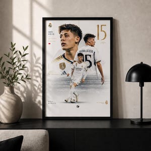 May include: A framed vertical poster featuring three images of soccer player Arda Güler in a white Real Madrid kit. The design includes the number 15 in gold, the text Arda Güler, Hala Madrid, and the Real Madrid club crest on a white background.