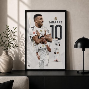 Puede incluir: Un póster enmarcado que presenta tres imágenes de Kylian Mbappé con la equipación blanca del Real Madrid. El diseño incluye el texto MBAPPÉ y el número 10 en una fuente negra grande. El jugador aparece en varias poses, incluido un retrato.