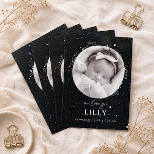 Könnte beinhalten: Eine Reihe von Babykarten mit einem schwarzen Sternenhintergrund. Jede Karte zeigt ein rundes Schwarz-Weiß-Foto eines schlafenden Babys, den Namen "LILLY" und den Text "we love you". Die Karten enthalten auch das Geburtsdatum, das Gewicht und die Größe des Babys in cm.