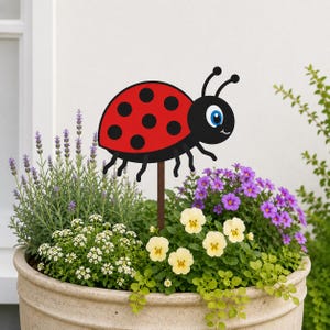 May include: A decorative garden stake featuring a cartoon ladybug with a bright red shell, black spots, and a black head with blue eyes. The ladybug is attached to a thin brown wooden stick, designed to be inserted into a potted plant or soil.