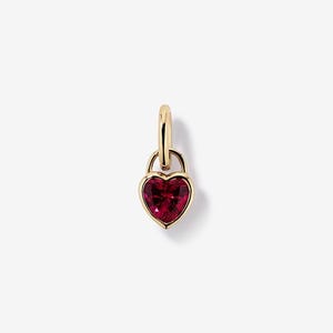 May include: A gold-toned heart-shaped pendant featuring a deep red faceted gemstone set within a polished metal frame. The heart is suspended from a small, smooth gold-toned circular bail, creating a simple and elegant jewelry charm design.