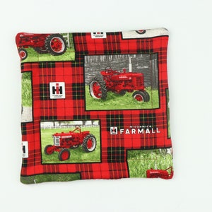 May include: Red and black plaid fabric with images of red tractors. The tractors have the text "McCormick Farmall" on them.