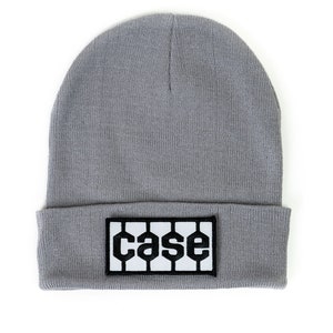 May include: A gray beanie hat with a folded brim. A black and white rectangular patch with the word "case" in a bold, stylized font is sewn onto the front of the hat. The hat is made of a soft, knitted material.
