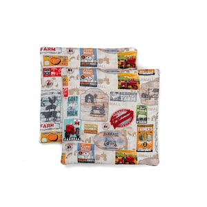 Puede incluir: Dos fundas de cojín de tela con temática de granja. Las fundas presentan un fondo blanco con una variedad de ilustraciones de temática de granja en rojo, azul, amarillo y verde, incluyendo tractores, graneros y animales de granja. El texto "Farm Market" y "Farmall" se repite en todo el diseño.