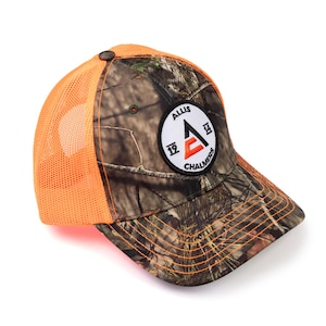 May include: A camouflage and orange trucker hat with a white circle patch that says "Allis Chalmers" with a red "A" inside the circle.