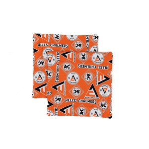 Puede incluir: Dos posavasos cuadrados Allis-Chalmers. Los posavasos tienen un fondo naranja con un patrón repetido del logotipo de Allis-Chalmers en blanco, negro y naranja. El logotipo incluye las letras "AC" y las palabras "Allis-Chalmers".