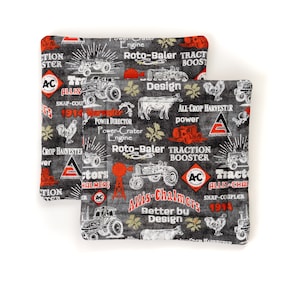 Puede incluir: Dos agarraderas cuadradas y acolchadas con un fondo negro que presenta diseños de tractores vintage blancos y rojos, animales de granja y texto que incluye "Allis-Chalmers" y "1914".