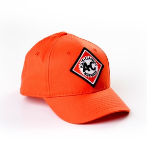 May include: An orange baseball cap with a black and white patch featuring the text "Allis-Chalmers" and the letters "AC" in a circle.