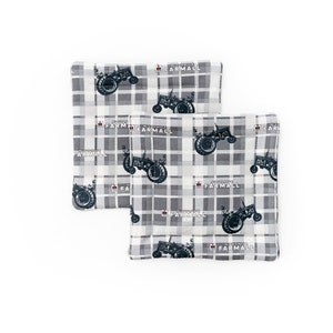 Puede incluir: Dos artículos cuadrados de tela con el tema del tractor Farmall. Presentan un patrón de cuadros grises y blancos con imágenes repetidas de un tractor negro y la palabra "Farmall" en rojo. Probablemente accesorios de cocina.