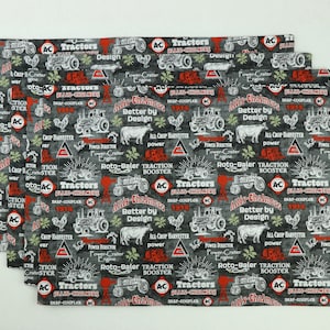 May include: A stack of five gray and red fabric placemats with a repeating pattern of vintage tractor illustrations and text that reads "Allis-Chalmers Tractors Better by Design".