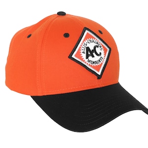 May include: Orange and black baseball cap with a diamond-shaped patch featuring the text "Allis-Chalmers AC Milwaukee".