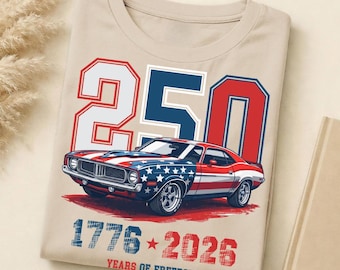May include: A beige t-shirt featuring a graphic of a classic muscle car painted with the American flag. Above the car is the number 250 in red, white, and blue. Below the car is the text 1776-2026 and the words YEARS OF FREEDOM in blue.