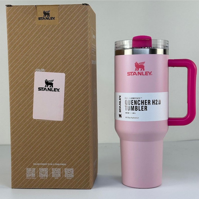 May include: A pink Stanley Quencher H2.0 Tumbler with a matching handle and lid. The tumbler is 40 oz and comes with a cardboard box. The box has the Stanley logo and product information.