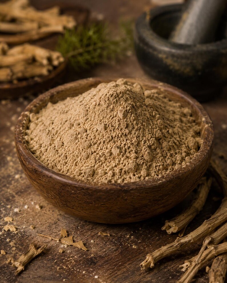May include: A wooden bowl filled with light brown powder, likely a spice or herb, sits on a wooden surface. Dried roots and a mortar and pestle are in the background. The scene suggests a natural, organic product, possibly for culinary or medicinal use.