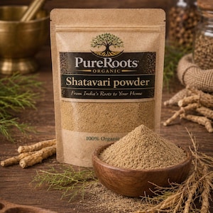 May include: A package of Shatavari powder from PureRoots Organic, with a wooden bowl of powder and a wooden spoon with seeds. The package has the text "Shatavari powder" and "From India's Roots to Your Home". The background includes herbs and roots.