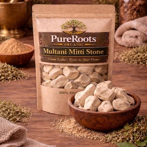 May include: A package of 'Pure Roots Organic' Multani Mitti Stone, with a clear window showing the stones. A wooden bowl filled with stones sits in front of the package. The text 'From India's Roots to Your Home' is visible.