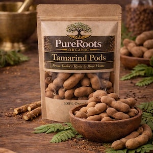 May include: A packet of PureRoots Organic Tamarind Pods is displayed on a wooden surface, with a wooden bowl filled with tamarind pods. The packaging features the brand name and product description. The image is a close-up shot.