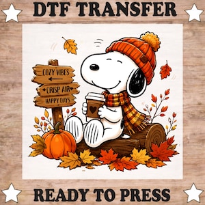 May include: A DTF transfer featuring a cartoon dog wearing an orange knit hat and a plaid scarf, holding a coffee cup. Beside the dog is a wooden signpost with the text Cozy Vibes, Crisp Air, and Happy Days, plus a pumpkin and autumn leaves.