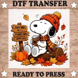 May include: A DTF transfer featuring a white cartoon dog wearing an orange knit hat and a plaid scarf, holding a coffee cup. Beside the dog is a wooden signpost with the text COZY VIBES, CRISP AIR, and HAPPY DAYS, an orange pumpkin, and autumn leaves.