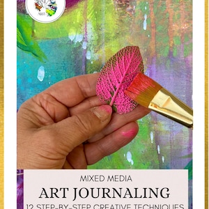 May include: A book cover titled Mixed Media Art Journaling 12 Step-By-Step Creative Techniques by Britt and Toni Art Book One. The cover features a hand painting a bright pink leaf with a brush against a vibrant green and purple background.