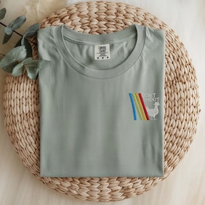 May include: A white ceramic mug with a black handle and the text "But First, Coffee" in a bold, black font. The mug is set against a blurred background, suggesting a cozy setting. The mug appears to be approximately 4 inches tall.