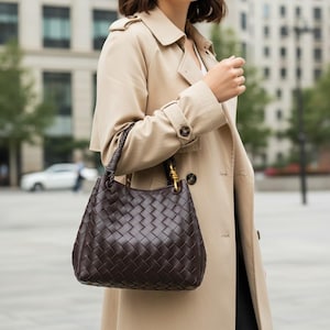 Peut inclure: Un sac &agrave; main marron fonc&eacute; dot&eacute; d'un motif en cuir tress&eacute; complexe. Le sac pr&eacute;sente une base arrondie structur&eacute;e et une poign&eacute;e tress&eacute;e unique fix&eacute;e au corps par des &eacute;l&eacute;ments m&eacute;talliques dor&eacute;s, assurant une prise en main pratique.