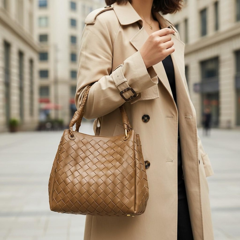 Peut inclure: Un sac &agrave; main marron de taille moyenne pr&eacute;sentant un motif en cuir tress&eacute; complexe sur tout l'ext&eacute;rieur. Le sac comprend deux anses en cuir tress&eacute; fix&eacute;es par des &eacute;l&eacute;ments m&eacute;talliques dor&eacute;s et une base structur&eacute;e avec de petits pieds.