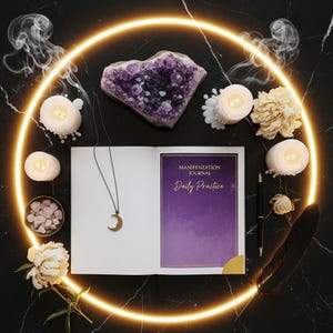 May include: An open journal with the text "Manifestation Journal Daily Practice" sits on a black marble surface, surrounded by candles, crystals, and a crescent moon necklace. A glowing yellow circle frames the arrangement.