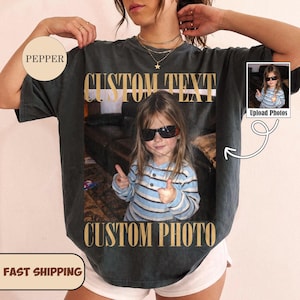 May include: A charcoal gray short-sleeve t-shirt featuring a large rectangular graphic print of a child wearing sunglasses and a blue striped shirt. The text CUSTOM TEXT appears above the photo and CUSTOM PHOTO appears below the photo.