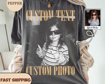 May include: A charcoal gray short-sleeve t-shirt featuring a black and white photograph of a child wearing sunglasses and giving a thumbs up. The text CUSTOM TEXT appears in tan above the photo, and CUSTOM PHOTO appears in tan below the photo.