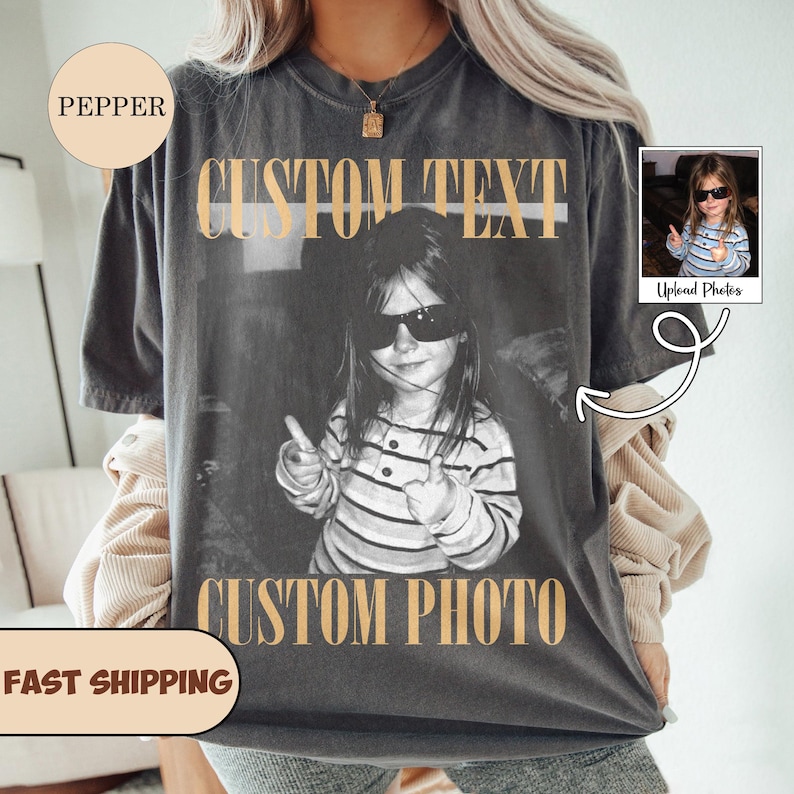 May include: A charcoal gray short-sleeve t-shirt featuring a black and white photograph of a child wearing sunglasses and giving a thumbs up. The text CUSTOM TEXT appears in tan above the photo, and CUSTOM PHOTO appears in tan below the photo.