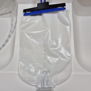 May include: A white ceramic mug with a black handle and the text "But First, Coffee" in a bold, black font. The mug is sitting on a wooden surface. The mug is approximately 4 inches tall.