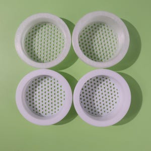 Op de afbeelding: Een witte keramische mok met een zwarte handgreep en de tekst "But First, Coffee" in een zwarte, vette letter. De mok staat op een wit oppervlak. De mok lijkt ongeveer 355 ml te bevatten.