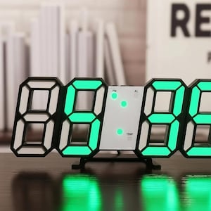 Peut inclure: Une horloge numérique moderne avec un cadre noir et des chiffres LED vert vif. L'horloge affiche l'heure dans un format grand et facile à lire. Elle a un design élégant et comprend des indicateurs PM, AL et TEMP.