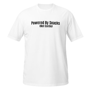 Puede incluir: Camiseta blanca con el texto "Powered By Snacks (Not Cardio)" impreso en negro. La camiseta tiene mangas cortas y cuello redondo. El texto está centrado en la parte delantera de la camiseta.