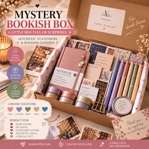 Puede incluir: Una caja de cartón que contiene un cuaderno de puntos A6 de tapa dura rosa, varios rollos de cinta decorativa, un clip de metal dorado, cinco bolígrafos de colores, una pequeña lata redonda y varias tarjetas impresas con texto.