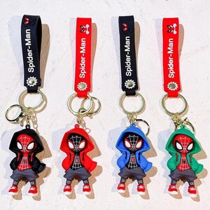 Może przedstawiać: Cztery breloczki do kluczy Spider-Man. Każdy breloczek przedstawia figurkę Spider-Mana w bluzie z kapturem w innym kolorze: czarnym, czerwonym, niebieskim i zielonym. Breloczki mają czarny lub czerwony pasek z napisem "Spider-Man".