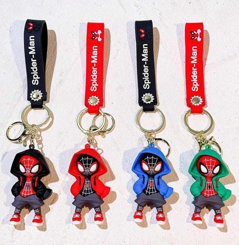 Może przedstawiać: Cztery breloczki do kluczy Spider-Man. Każdy breloczek przedstawia figurkę Spider-Mana w bluzie z kapturem w innym kolorze: czarnym, czerwonym, niebieskim i zielonym. Breloczki mają czarny lub czerwony pasek z napisem "Spider-Man".