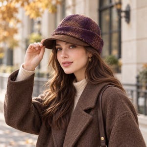 May include: A structured cap featuring a deep purple and orange plaid pattern with a solid brown brim. The hat has a rounded crown and a short, stiff visor, constructed from a textured fabric that sits securely on the head with a folded edge.